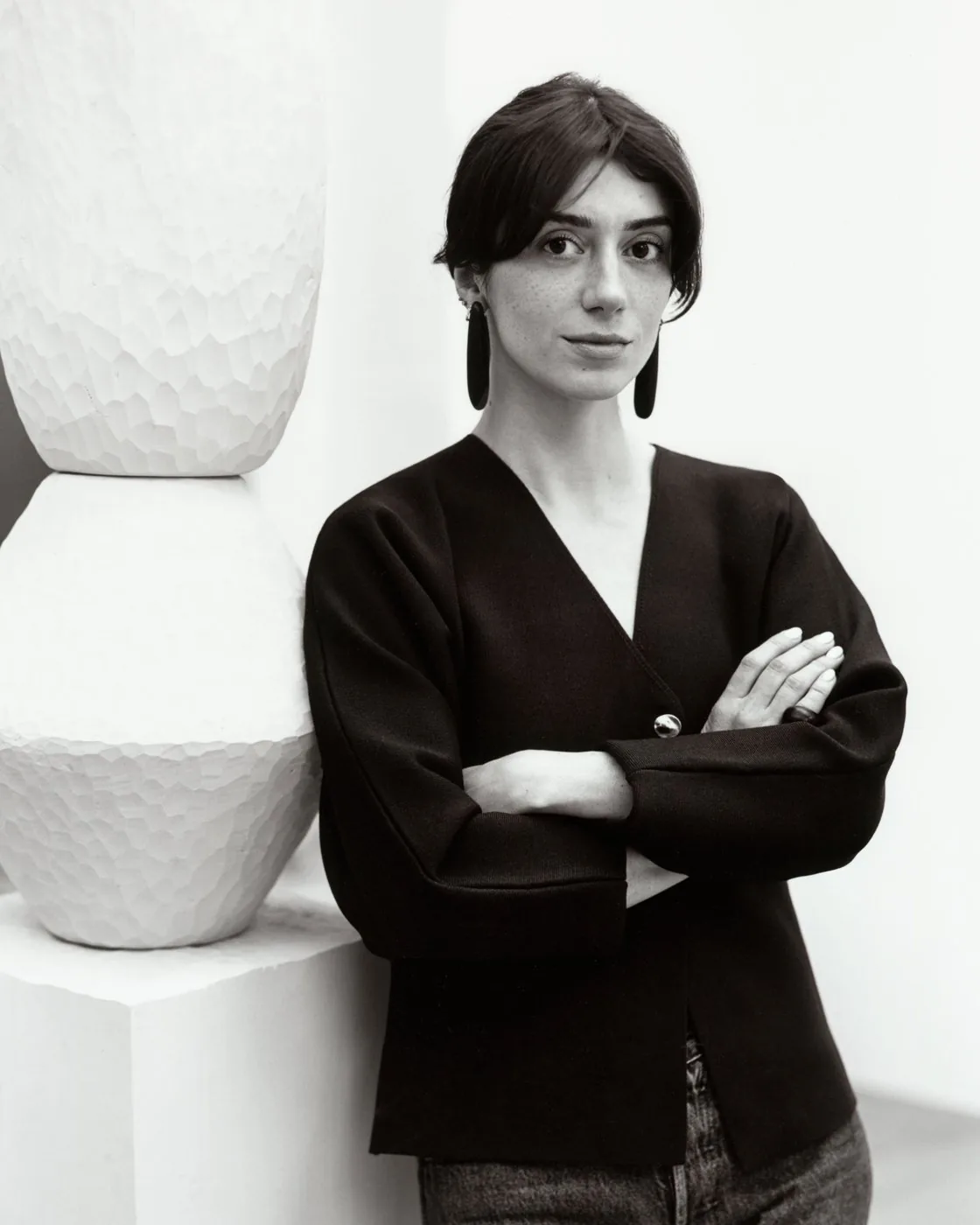 Portrait of Alice Damiens leaning against a white carved wooden totem