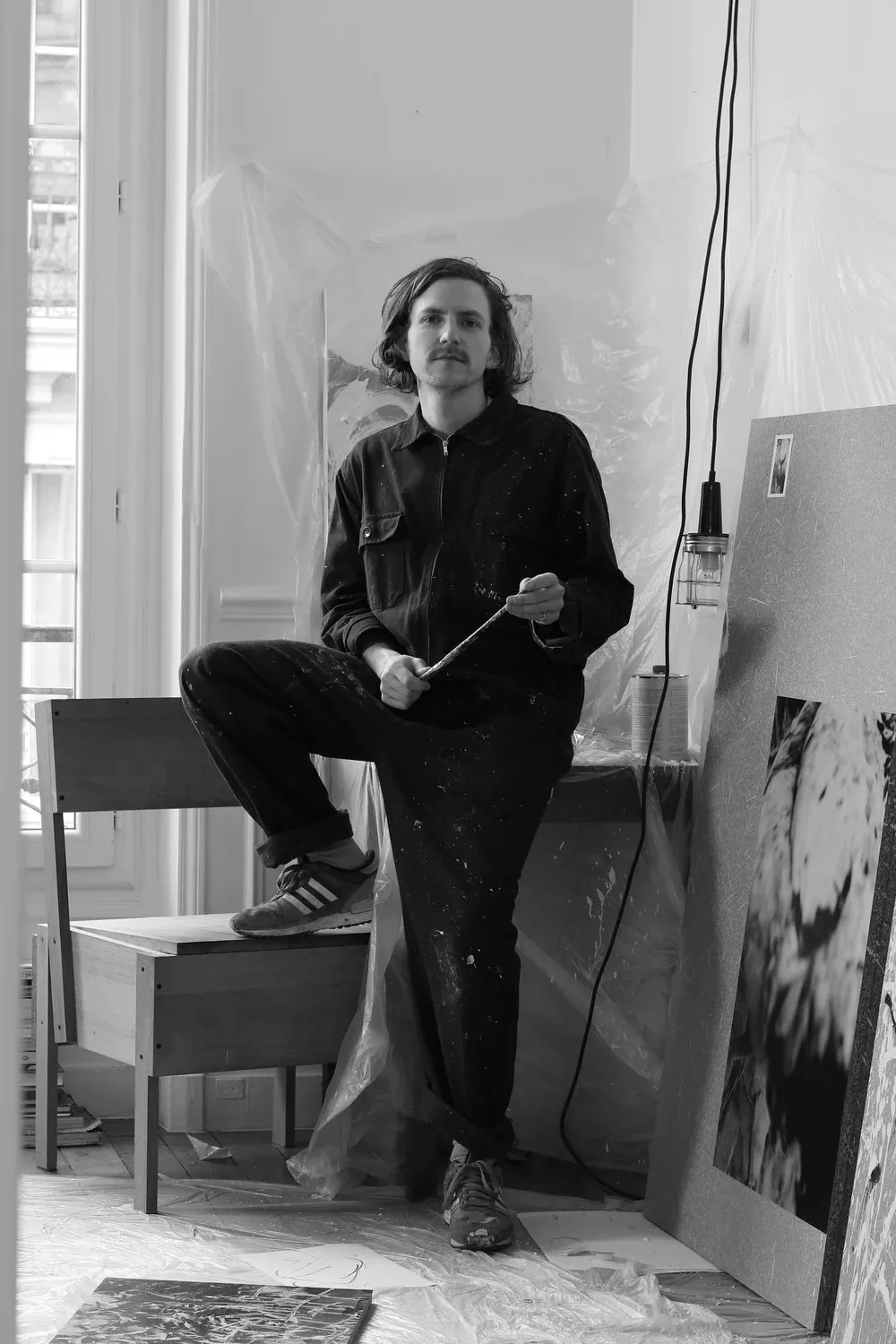 Daniel Costa seated in his studio, holding a brush